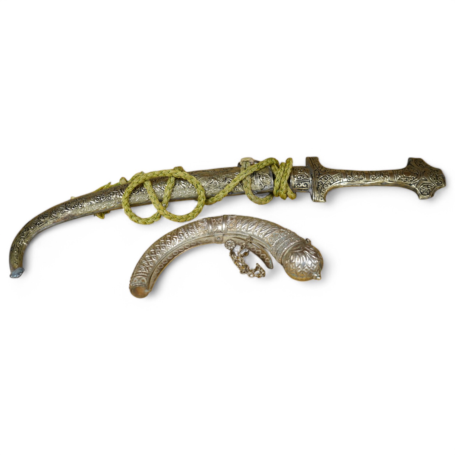 An Omani silver spice box in the form of a curved powder flask, together with a Moroccan dagger Jambiya with nickel hilt and sheath, both 20th century. Condition - fair.